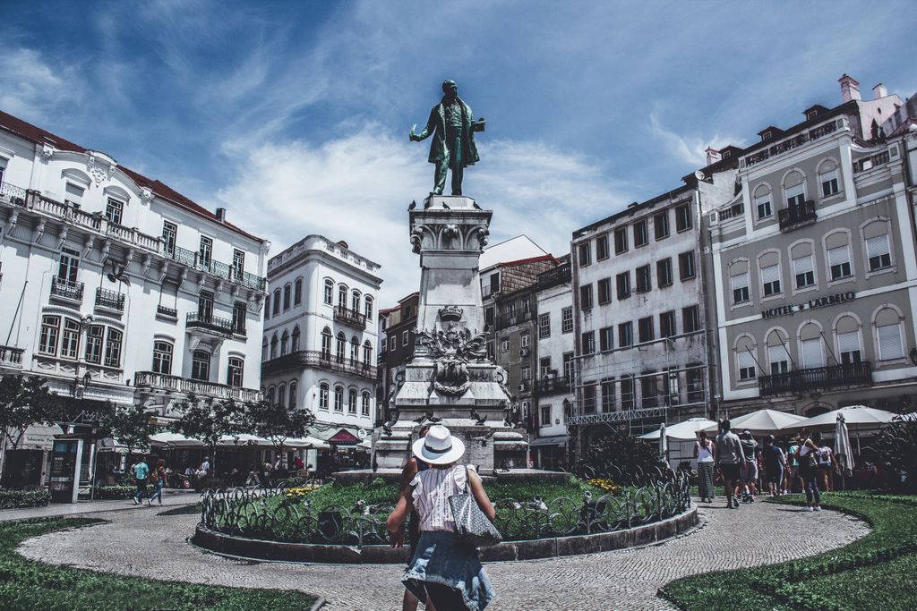 Monumental statue in a bustling Porto square, capturing local life and architecture.
