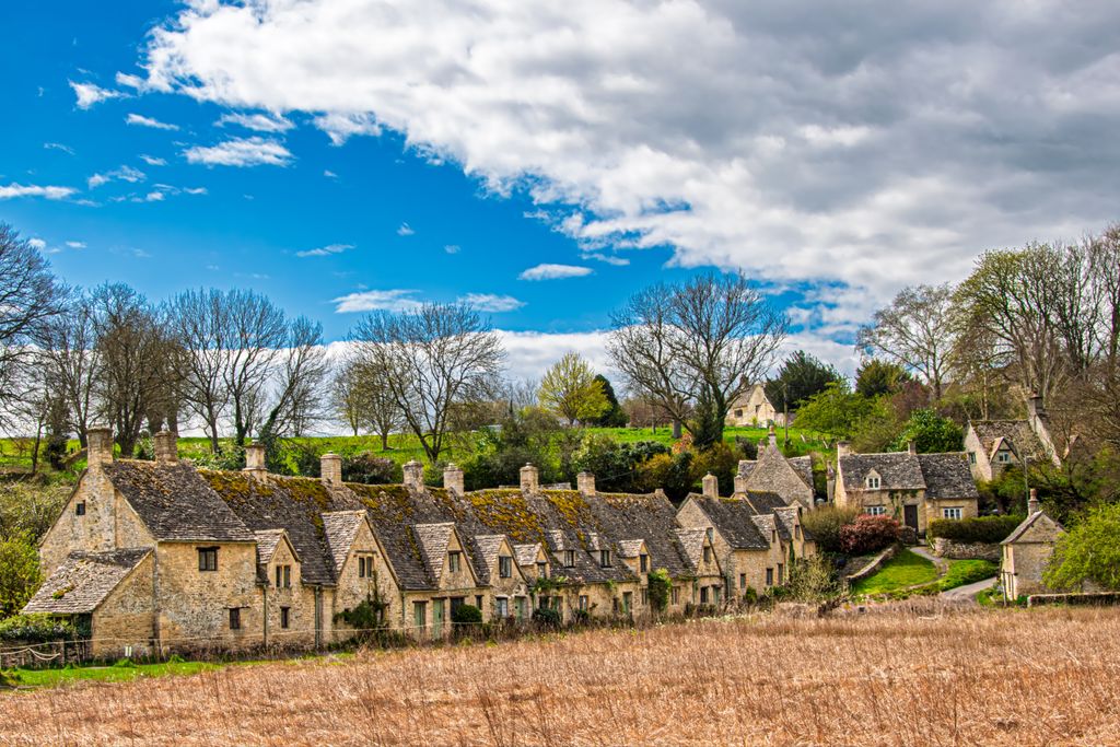 Cotswolds Travel Guide: Picturesque Cotswold village with historic stone houses and vibrant spring scenery.