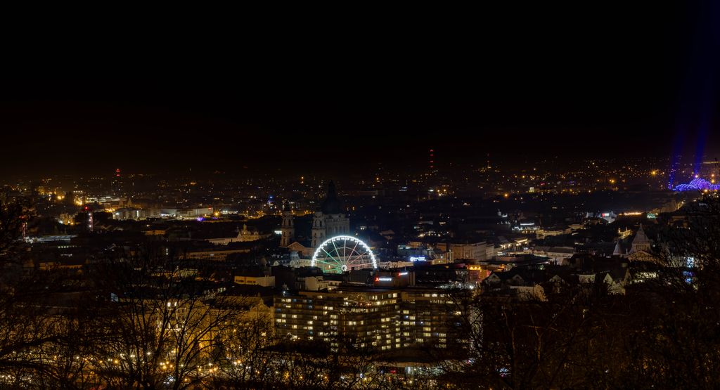 Stunning city skyline at night featuring a glowing Ferris wheel and bright urban lights.
