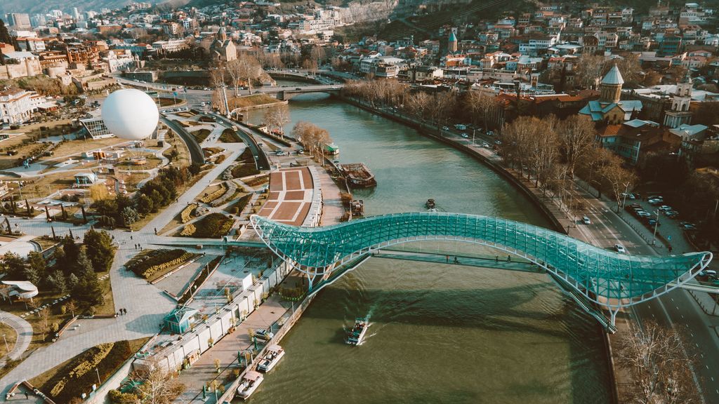 Aerial view of Peace Bridge over Kura River in Tbilisi, Georgia, showcasing urban landscape.