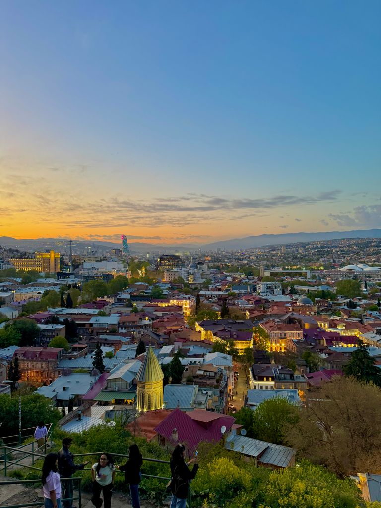 Captivating sunset view of Tbilisi's vibrant cityscape with scenic skyline and people enjoying the moment.