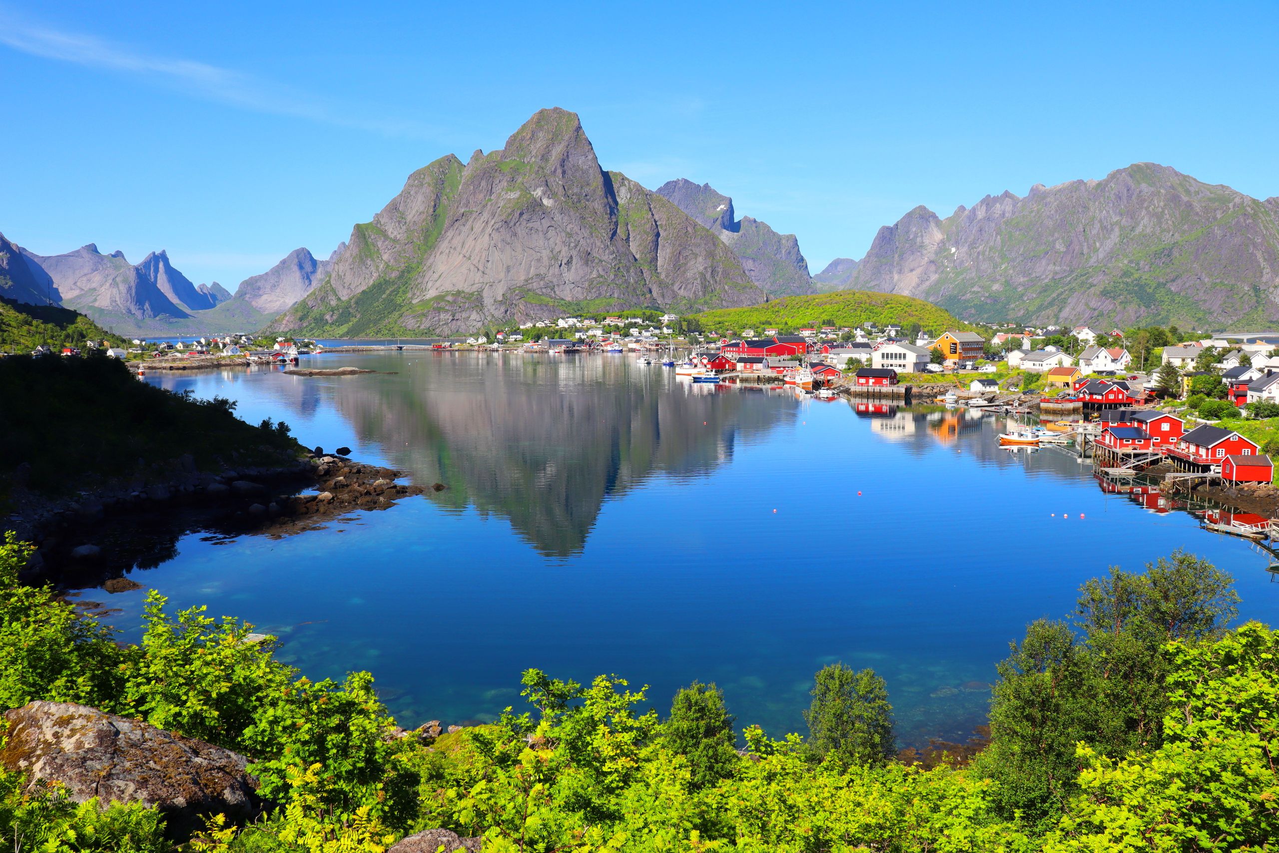 Scenic landscape of Lofoten Islands with clear blue skies and reflections on the water.