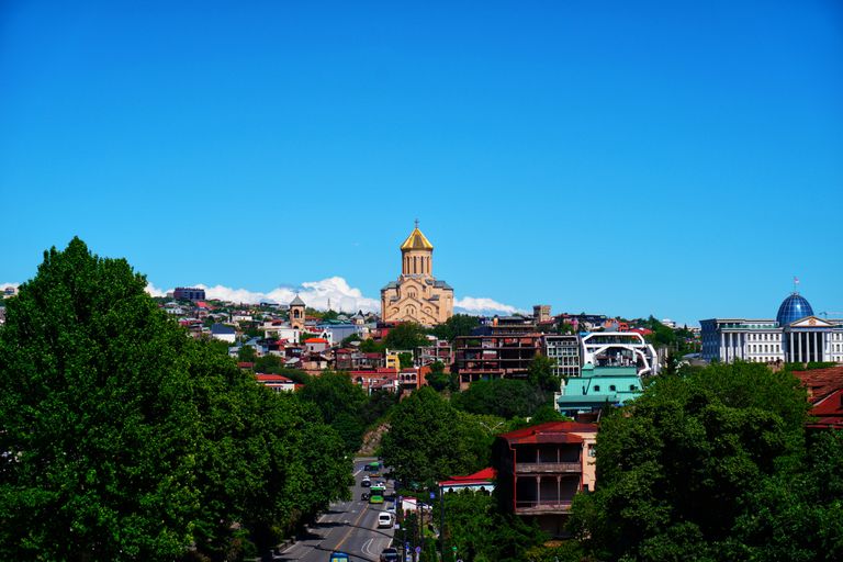 Stunning panorama of Tbilisi cityscape featuring the Holy Trinity Cathedral under a clear blue sky.
