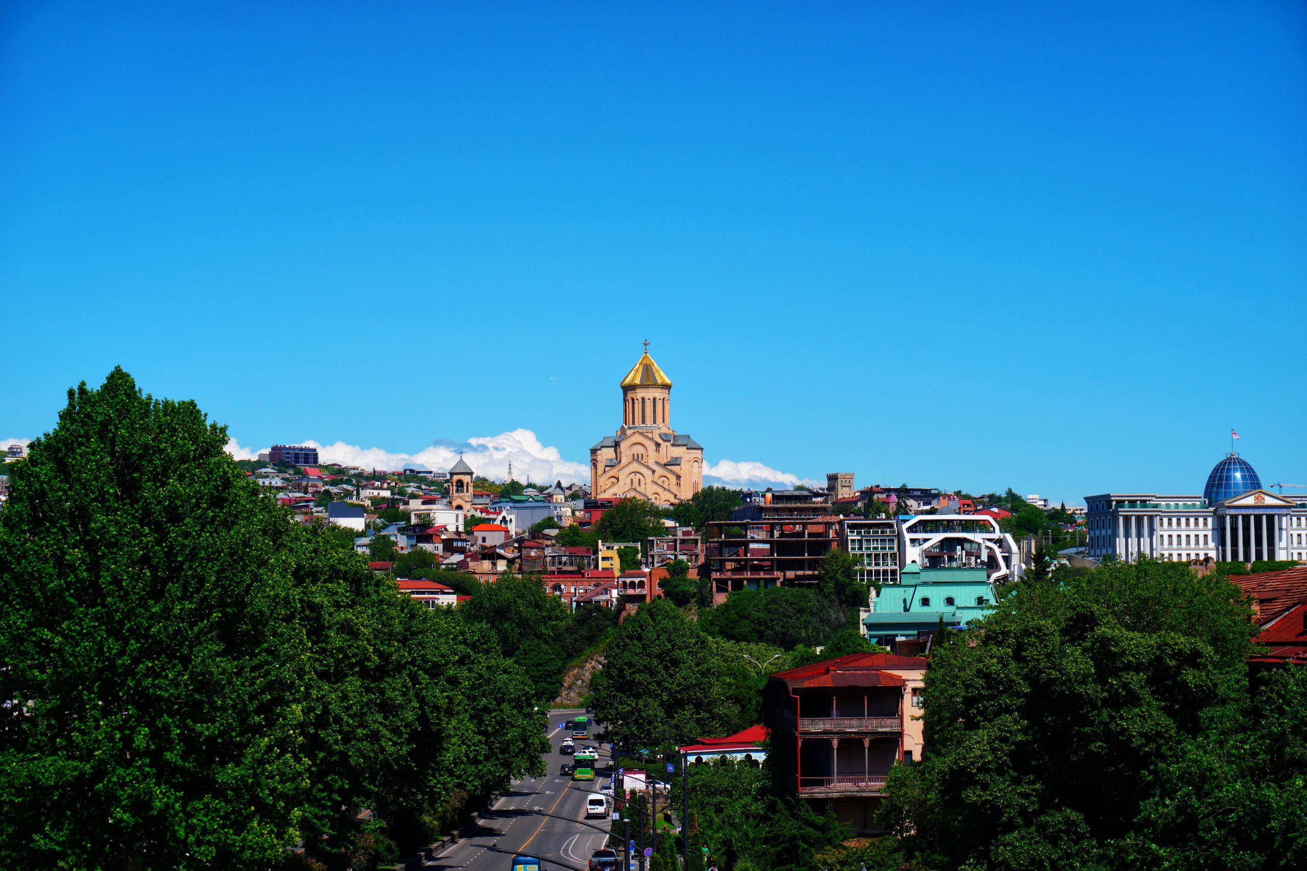 Stunning panorama of Tbilisi cityscape featuring the Holy Trinity Cathedral under a clear blue sky.